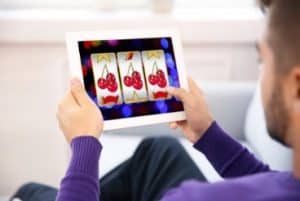 Homme jouant a la machine a sous sur tablette - Casinosansdepot.net